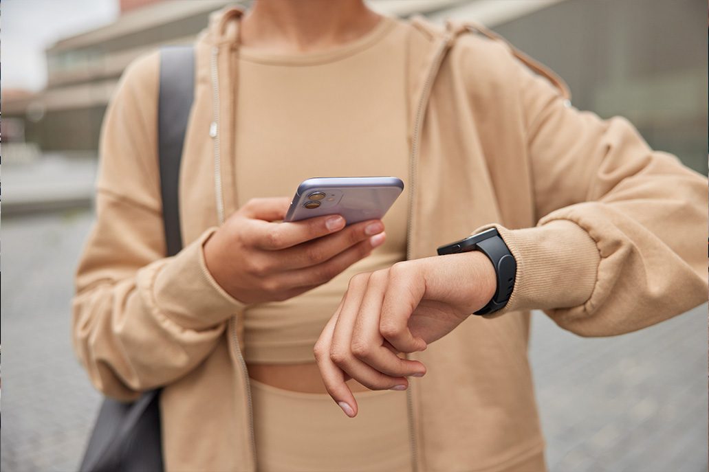 Person, die auf ihr Mobiltelefon schaut und die Uhrzeit überprüft.