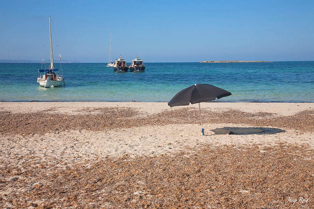 Es Carbó beach with boats and sunshades